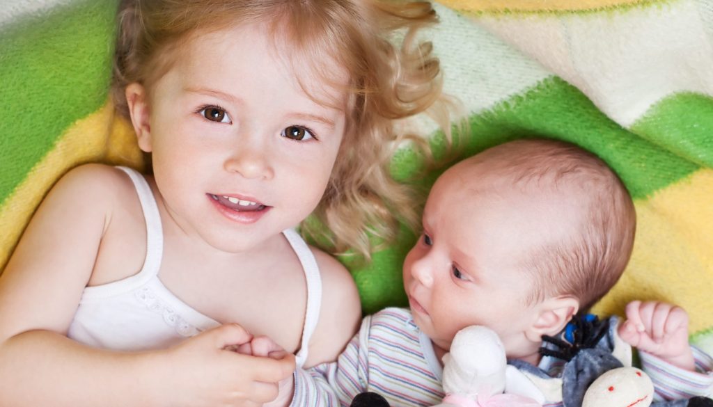 Happy,Little,Girl,Lovingly,Holding,The,Hand,Of,A,Newborn