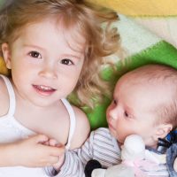 Happy,Little,Girl,Lovingly,Holding,The,Hand,Of,A,Newborn