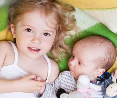 Happy,Little,Girl,Lovingly,Holding,The,Hand,Of,A,Newborn